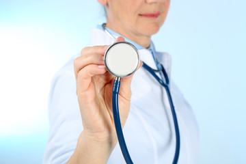 Professional doctor with stethoscope on blue background