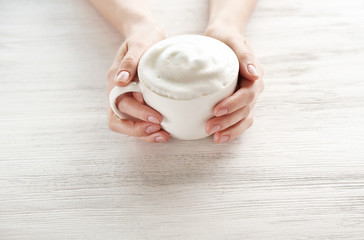 Woman holding cup of coffee on wooden background