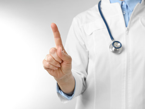 Professional doctor making gesture on light background