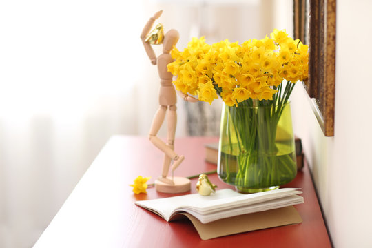 Beautiful bouquet of yellow narcissus on chest of drawers