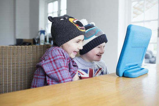 Boy With Downs Syndrome And Brother Using Computer At Home