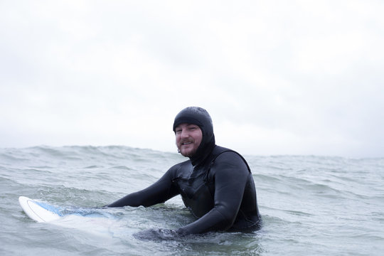 Surfer Wearing Wetsuit Floating With Board In Wintery Sea