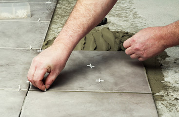 Home improvement, - close-up of handyman laying tile