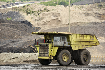 Green excavator loading soil on a truck at mine back lit