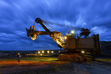 The worker man and Yellow excavator loading soil a truck at mine back lit on twilight after sunset © saravut