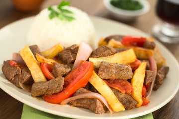 Peruanisches Gericht namens Lomo Saltado zubereitet aus Rindfleisch, Tomaten, Zwiebeln und Pommes, serviert mit Reis (Selektiver Fokus, Fokus ein Drittel in das Gericht)