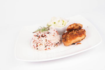 Pork chop (covered in breadcrumbs), three color rice and cucumber salad decorated with dill on a plate on white background