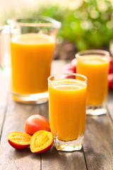 Frischgemachter Saft aus Tamarillo oder Baumtomate (lat. Solanum betaceum) (Selektiver Fokus, Fokus auf den vorderen Glasrand)