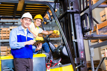 Asian lift truck driver and foreman in storage © Kzenon