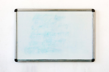 Old whiteboard for office with traces of stains and spots. Writing board hanging on the old dirty...