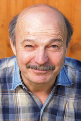 older man squinting from the sun. Good mood during the holidays