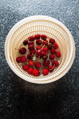 Wash fresh ripe Cherry Fruit in Salad spinner. on a black marble