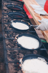 The pancakes are fried in a pan on the coals