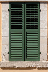 Closed green window on beige wall