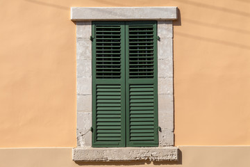 Closed green window on beige wall