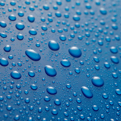 Glistening water droplets on waxed blue metal