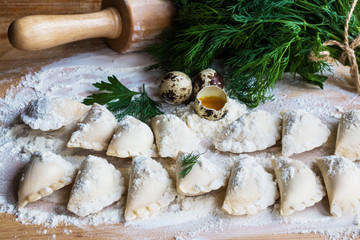 Raw dumplings, flour, eggs on a wooden board.