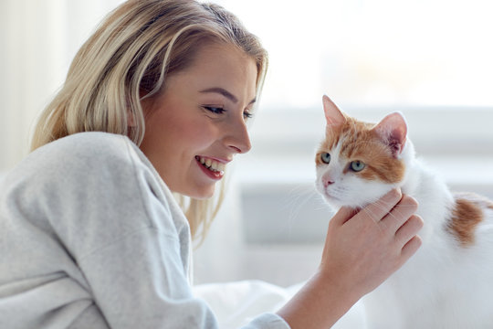 Happy Young Woman With Cat In Bed At Home