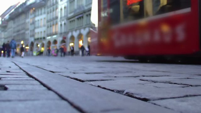 Modern tram passing crowded street in old city downtown, public transportation