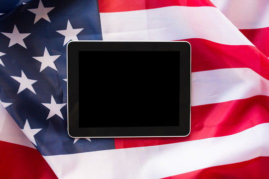 close up of tablet pc computer on american flag