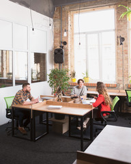 Picture of happy business people working in office. Two women communicating about business while their colleague man listening to them.