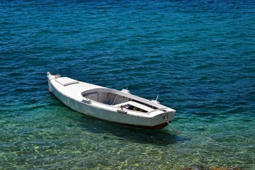 Tiny wooden boat on an azure sea