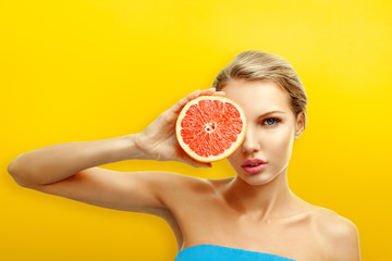 Young woman with fruits on bright orange background