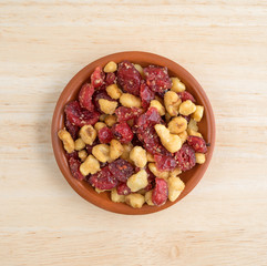 Cranberries and walnuts in a small bowl on a wood table top view.