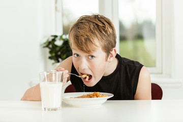 Teenage Boy Eating Breakfast Cereal in Morning