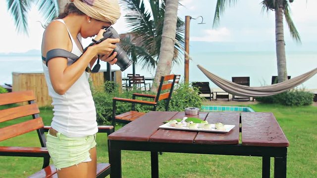 Girl photographer shooting food in restaurant outdoors