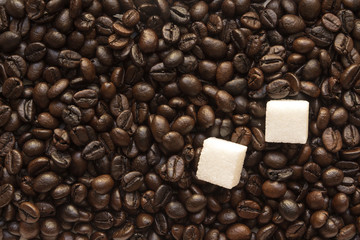 pieces of white sugar in coffee roasted beans Brown background
