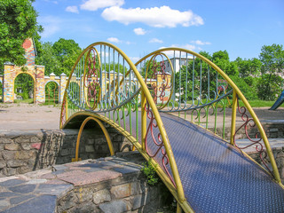 Декоративный мостик с ажурными перилами перекинут через чашу фонтана на детской площадке