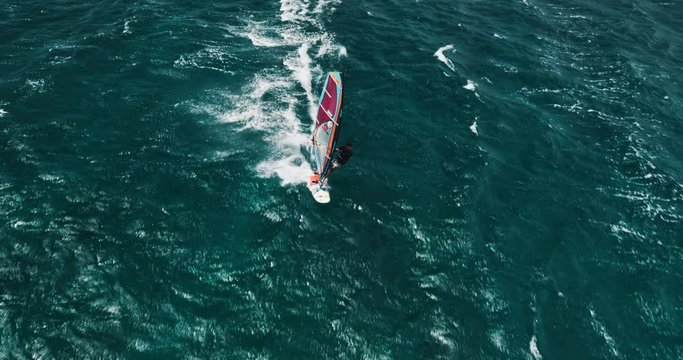 Aerial view of windsurfer gliding across blue ocean, extreme sport