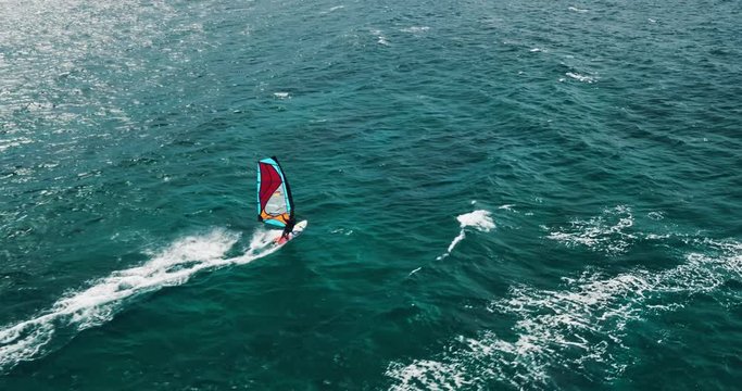 Aerial view of windsurfer gliding across blue ocean, extreme sport