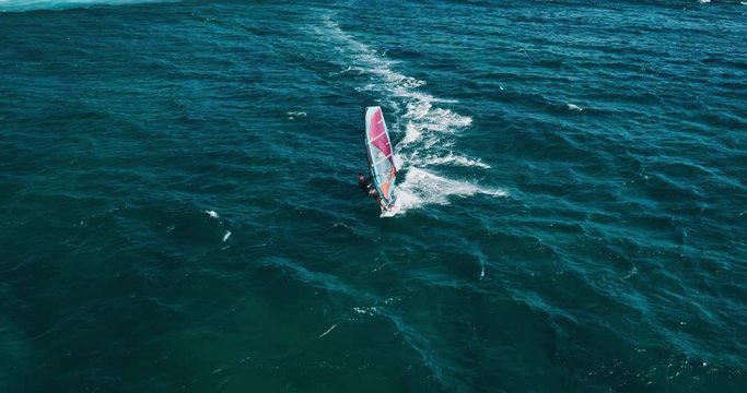 Aerial view of windsurfer gliding across blue ocean, extreme sport
