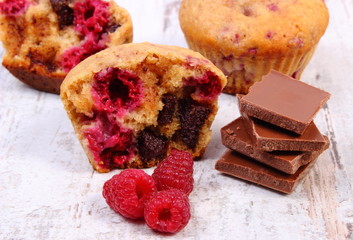 Fresh baked muffins with raspberries and chocolate on wooden background, delicious dessert