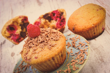 Vintage photo, Baked muffins with raspberries and grated chocolate on wooden background, delicious dessert