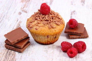 Fresh baked muffins with raspberries and chocolate on wooden background, delicious dessert