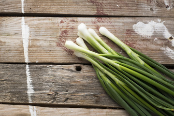bunch of fresh young green spring onion on a simple wooden background in rustic style