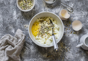 Cooking whole grain multi seed bread, raw ingredients - whole wheat flour, eggs, ricotta cheese, seeds, on a grey stone background. Baking background