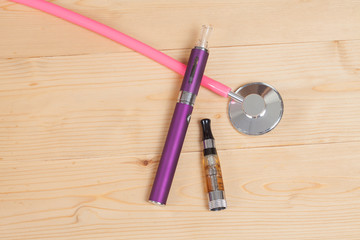 stethoscope and e- cigarette on wood table