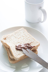 Chocolate cream with sliced bread on white dish and pink fabric