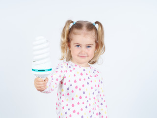 Little girl shows a large energy-saving light bulbs.