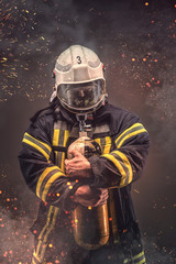 Fototapeta premium Firefighter in helmet and mask holds oxygen tanks.
