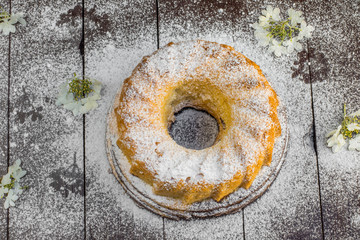 Obraz na płótnie Canvas Top View on Bundt Cake with Sugar and Flower on a Dark Wood Tabl