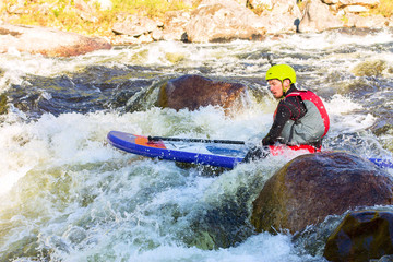 The man supsurfing on the rapids of the mountain river