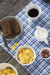 Healthy breakfast. Cornflakes, milk, cup of black coffee and slice chocolate cake