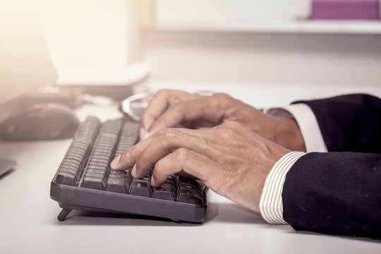 Businessman hand typing on keyboard and working in office