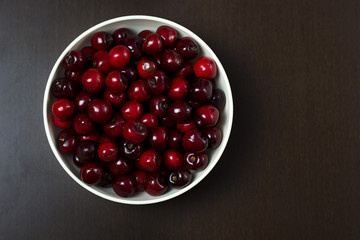 Cherries in bowl isolated on dark background