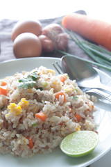 A dish of fried rice, carrot and egg on brown fabric, spoon, fol